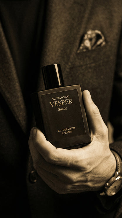 Hand holding a Calvin Klein Vesper perfume bottle against a dark background